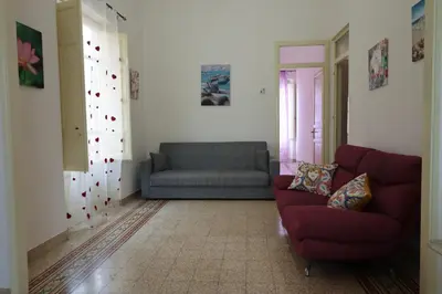 a living room with a red couch and a gray sofa at Holiday House Marconi in Castellammare del Golfo