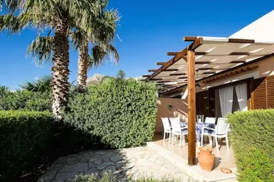 a patio with a table and chairs under a pergola at Villa Scirocco Macari in Macari