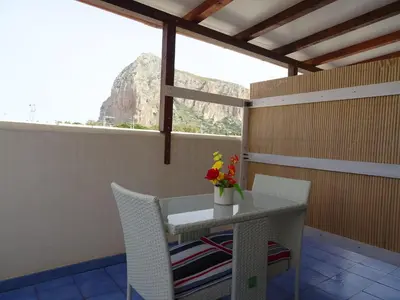 a table and chairs with a vase of flowers on a balcony at B&B Le Onde Del Mare in San Vito lo Capo