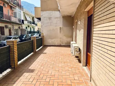a brick sidewalk next to a building with parked cars at Domus Aurea in Isola delle Femmine