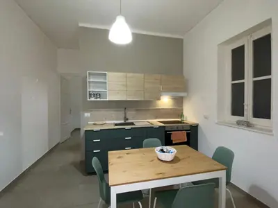 a kitchen with a table and chairs in a room at CasALE Sampó in Palermo