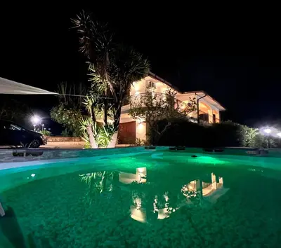 a circular pool of green water in a park at night at Villa La Terrazza Sul Mare di Trabia - Location fra Palermo e Cefalù in Trabia