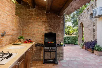 an outdoor kitchen with a grill in a brick wall at Cleo - Villa Siciliana in Partinico