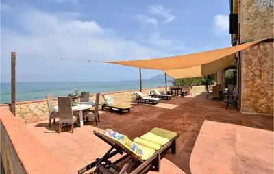 a patio with chairs and tables with the ocean in the background at Awesome Home In Trappeto With Wifi in Trappeto