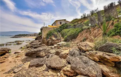 a group of rocks on a beach with a house at Awesome Home In Trappeto With Wifi in Trappeto