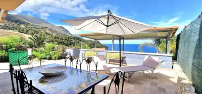 a table and chairs with an umbrella on a patio at Casa Richilde in Scopello