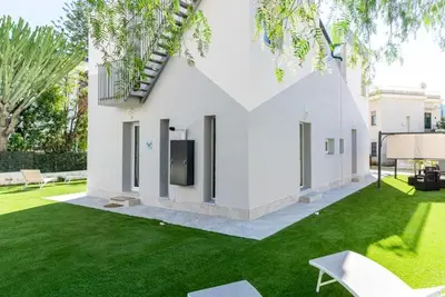 a white house with a yard with green grass at 3B Mondello Apartments in Palermo