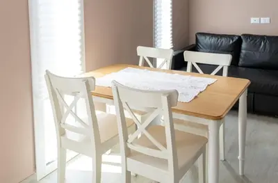 a dining room table with white chairs and a couch at 3B Mondello Apartments in Palermo