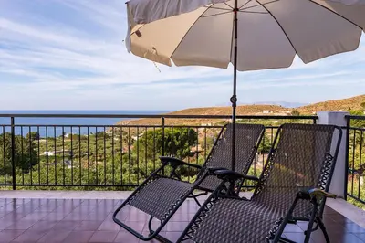 an umbrella and two chairs on a balcony with the ocean at Villa Duca Country House in Castellammare del Golfo