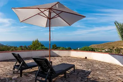 a patio with two chairs and an umbrella at Villa Duca Country House in Castellammare del Golfo