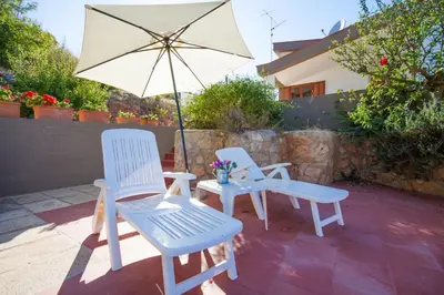two chairs and a table and an umbrella on a patio at Villa Duca Country House in Castellammare del Golfo