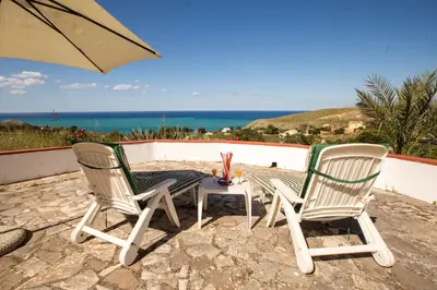 a patio with two chairs and a table with an umbrella at Villa Duca Country House in Castellammare del Golfo