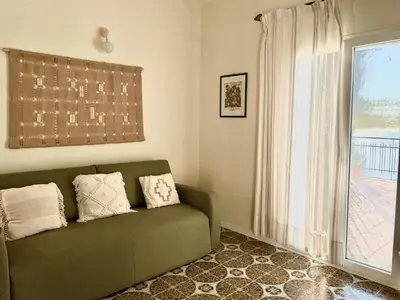 a living room with a green couch and a window at Il Poggio Retreat - Cefalù in Cefalù