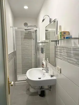 a white bathroom with a sink and a shower at STABILE APARTMENT in Palermo