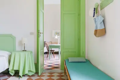 a bedroom with a green door and a table at Tonnara Foderà di Magazzinazzi in Alcamo