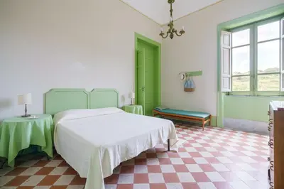 a green and white bedroom with a bed and a table at Tonnara Foderà di Magazzinazzi in Alcamo