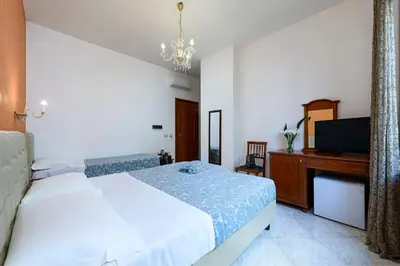 a bedroom with a bed and a desk with a laptop at Araba Fenice Hotel in San Vito lo Capo
