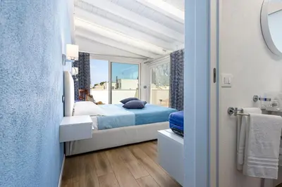 a sliding glass door with chairs and plants on a balcony at Araba Fenice Hotel in San Vito lo Capo