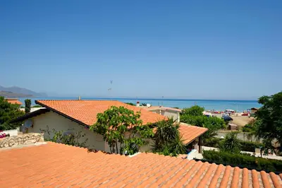 a building with an orange roof with the ocean in the background at Casa Vacanze Spiaggia Playa in Castellammare del Golfo