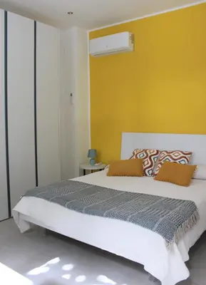 a bedroom with a large bed with a yellow wall at Villa Mercurio Mondello in Mondello