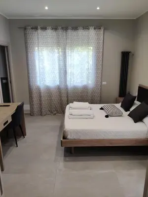 a bedroom with a bed with white sheets and a desk at Villa Mercurio Mondello in Mondello