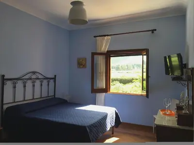 a blue bedroom with a bed and a window at Baglio Buccellato in Scopello