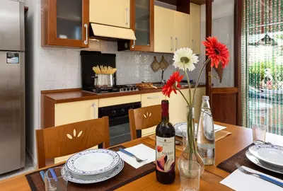 a kitchen with a table with a bottle of wine and flowers at Casa Karuscia in San Vito lo Capo