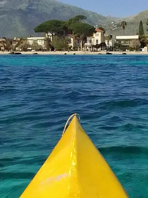 a yellow kayak in the water next to a beach at La casetta di rosario mondello in Palermo