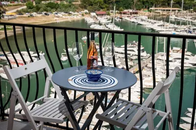 a table with glasses and a bottle of wine on a balcony at La suite del Golfo in Castellammare del Golfo