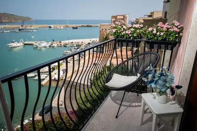 a balcony with chairs and a view of a harbor at La suite del Golfo in Castellammare del Golfo