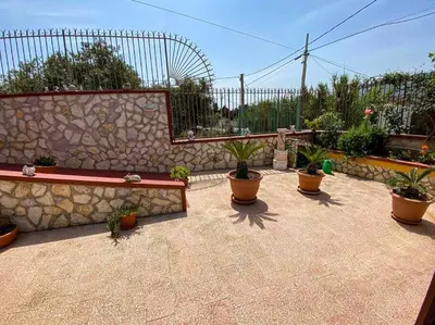 a patio with potted plants and a stone wall at Casa Vacanze Villino Nando in Palermo