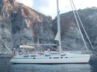 a white sailboat in the water next to a mountain at Gloria Sailing in Castellammare del Golfo