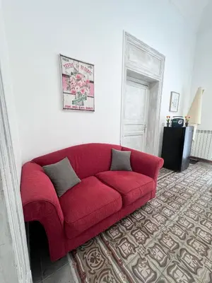a red couch in a living room with a rug at Casetta Alice in Palermo