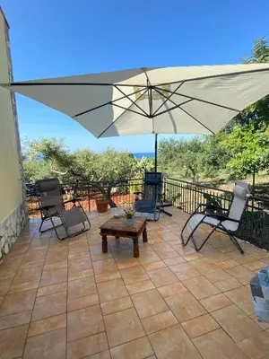a patio with an umbrella and chairs and a table at Villa L'orizzonte di calabianca in Castellammare del Golfo