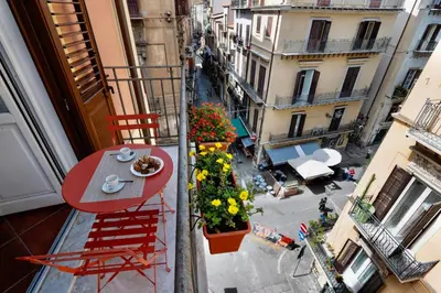 an apartment balcony with a table and chairs and flowers at Pothos House in Palermo