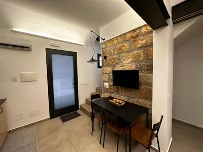 a dining room with a table and a stone wall at Le Gemelle Diverse in Cinisi