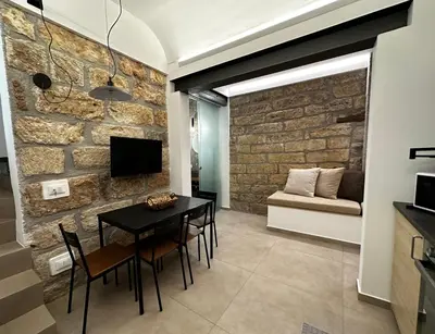 a dining room with a brick wall and a table and chairs at Le Gemelle Diverse in Cinisi