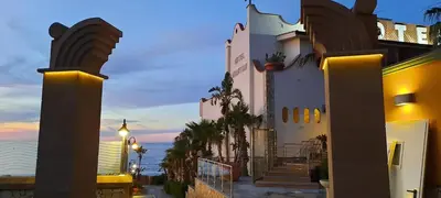 a building with a view of the ocean at dusk at Hotel La Martinica in Ficarazzi