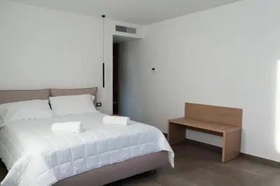 a bedroom with a white bed and a wooden table at Hotel La Martinica in Ficarazzi