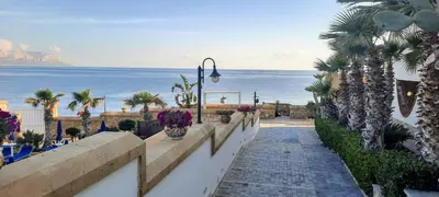 a pathway leading to a beach with palm trees and the ocean at Hotel La Martinica in Ficarazzi