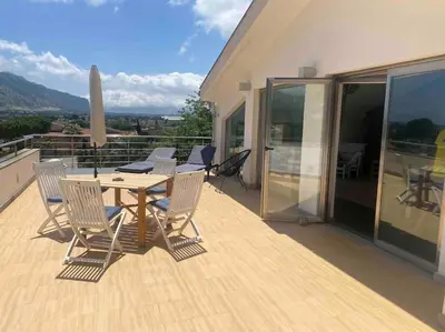 a wooden deck with a table and chairs on a balcony at Villa Elloise in Palermo