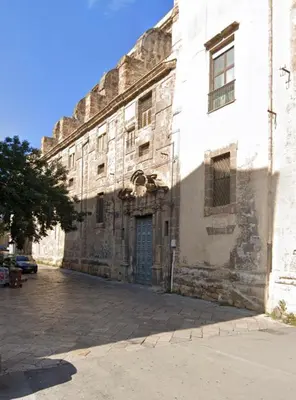 a man and woman walking down a street with luggage at Porta dei Greci in Palermo