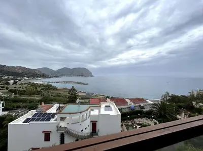 a white building with solar panels on it next to the water at La Scalinatella di Mondello in Palermo