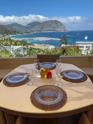 a table with two plates and wine glasses on it at La Scalinatella di Mondello in Palermo