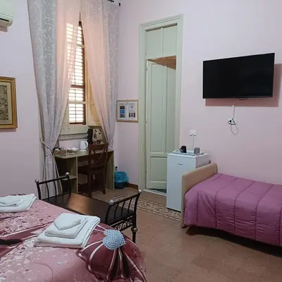 a room with two beds and a tv on the wall at DayBreak B&B in Palermo