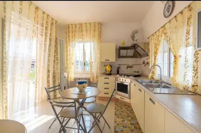 a kitchen with a table and chairs and a kitchen with a sink at Casa vacanze Elisir Del Golfo in Alcamo