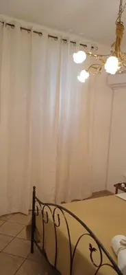 a bedroom with a bed and a window with white curtains at AI CANTIERI in Palermo