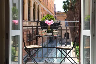 a balcony with two chairs and a table with flowers on it at Alle Absidi della Cattedrale in Palermo