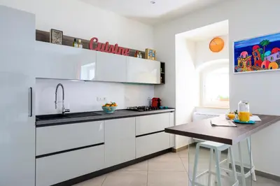 a kitchen with white cabinets and a wooden table at Tomasi Apartment Palermo in Palermo