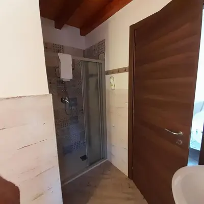 a bathroom with a shower and a wooden door at Enzo'S Suite in Palermo